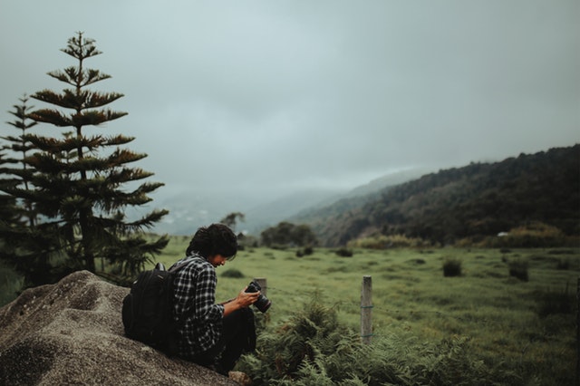 man-sitting-near-pine-tree-under-cloudy-sky-1448471